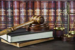 Allegory of justice Wood gavel, soundblock, scales and stack of old books against the background of a row of antique books bound in leather